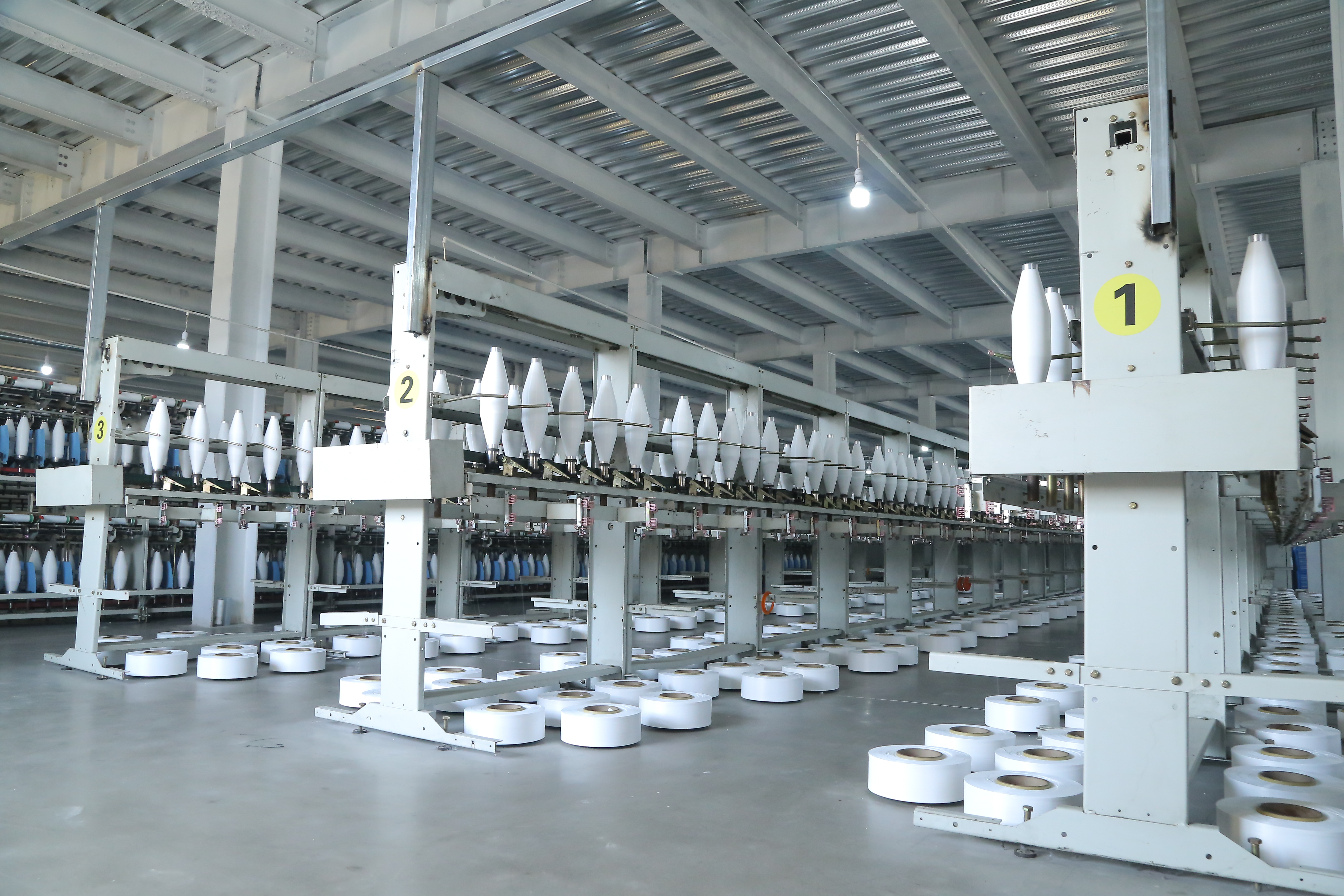 Rows of twisting machine bobbins in the twisting workshop